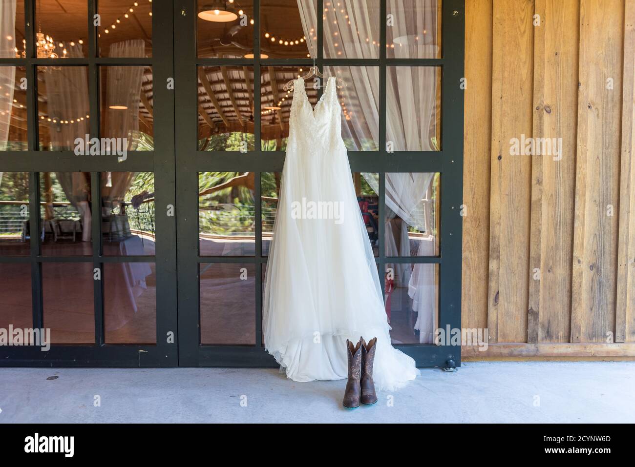 Elegant wedding dress hanging on the window and cowboy boots next to it  Stock Photo - Alamy