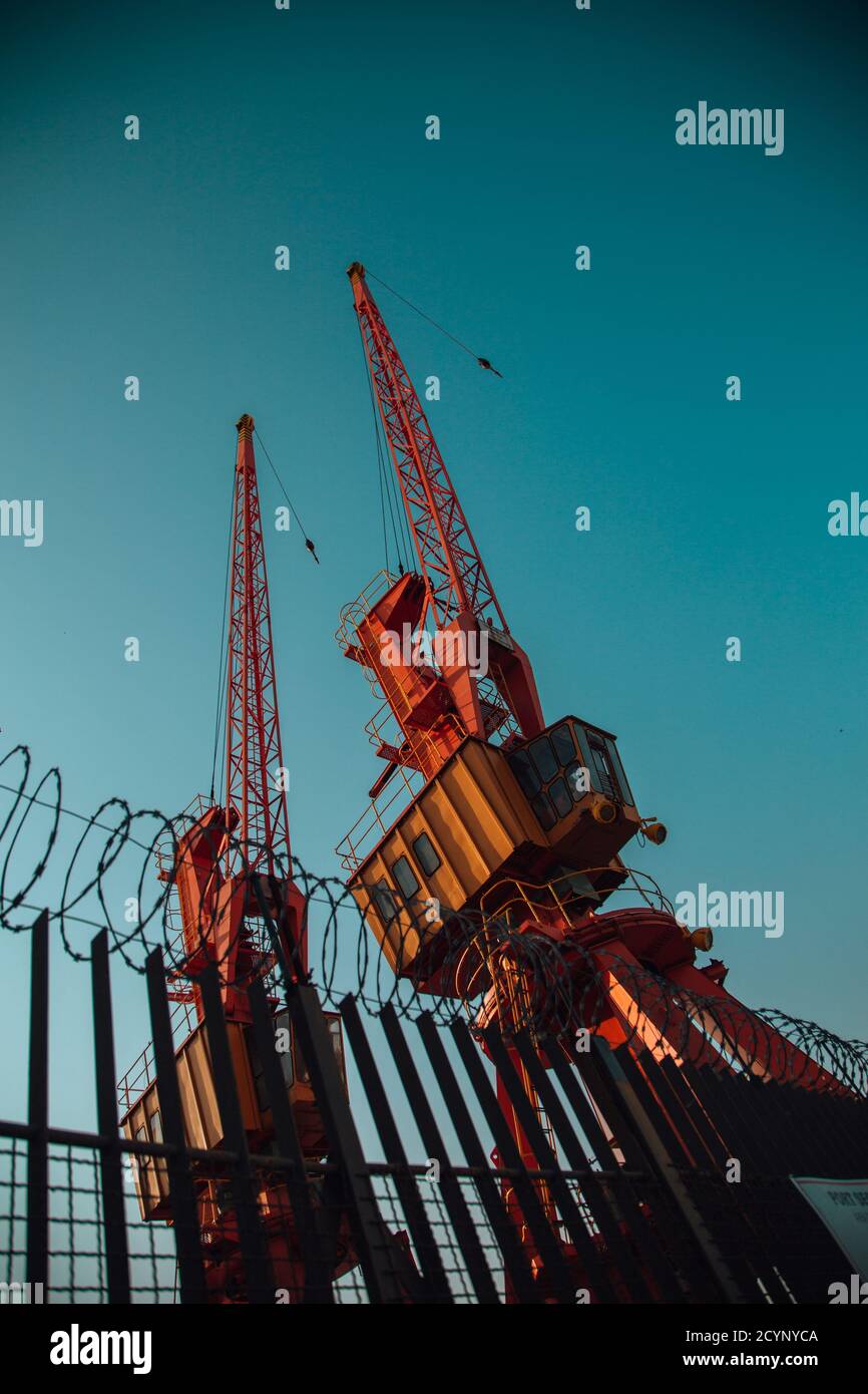 Vertical low angle shot of red cranes on a blue sky background Stock ...