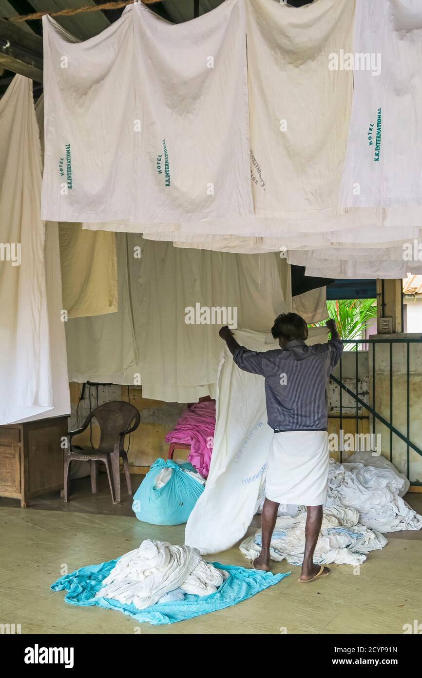 Man wearing a lungi hanging sheets to dry at the Dhobi Khana, a rare