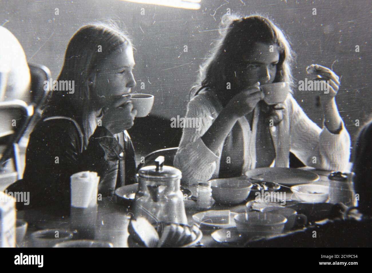 Fine 1970s vintage black and white photography of two young ladies eating lunch at the cafeteria. Stock Photo
