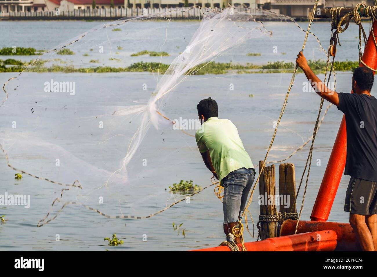 Fisherman casting weighted circular hand net on the waterfront of