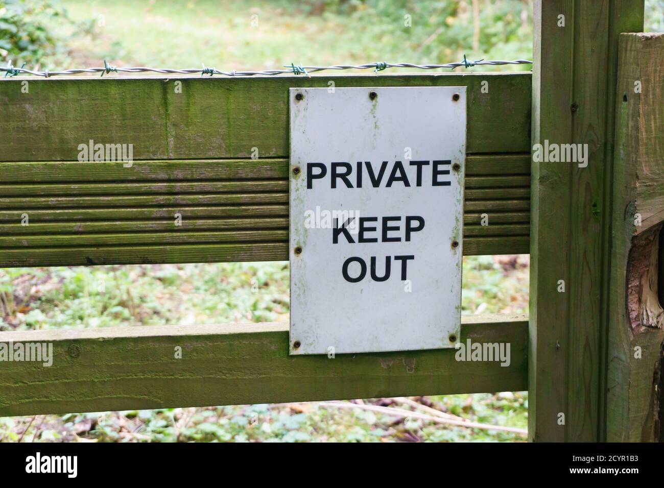 Private keep out sign on a gate with barbed wire on a forest trail Stock Photo