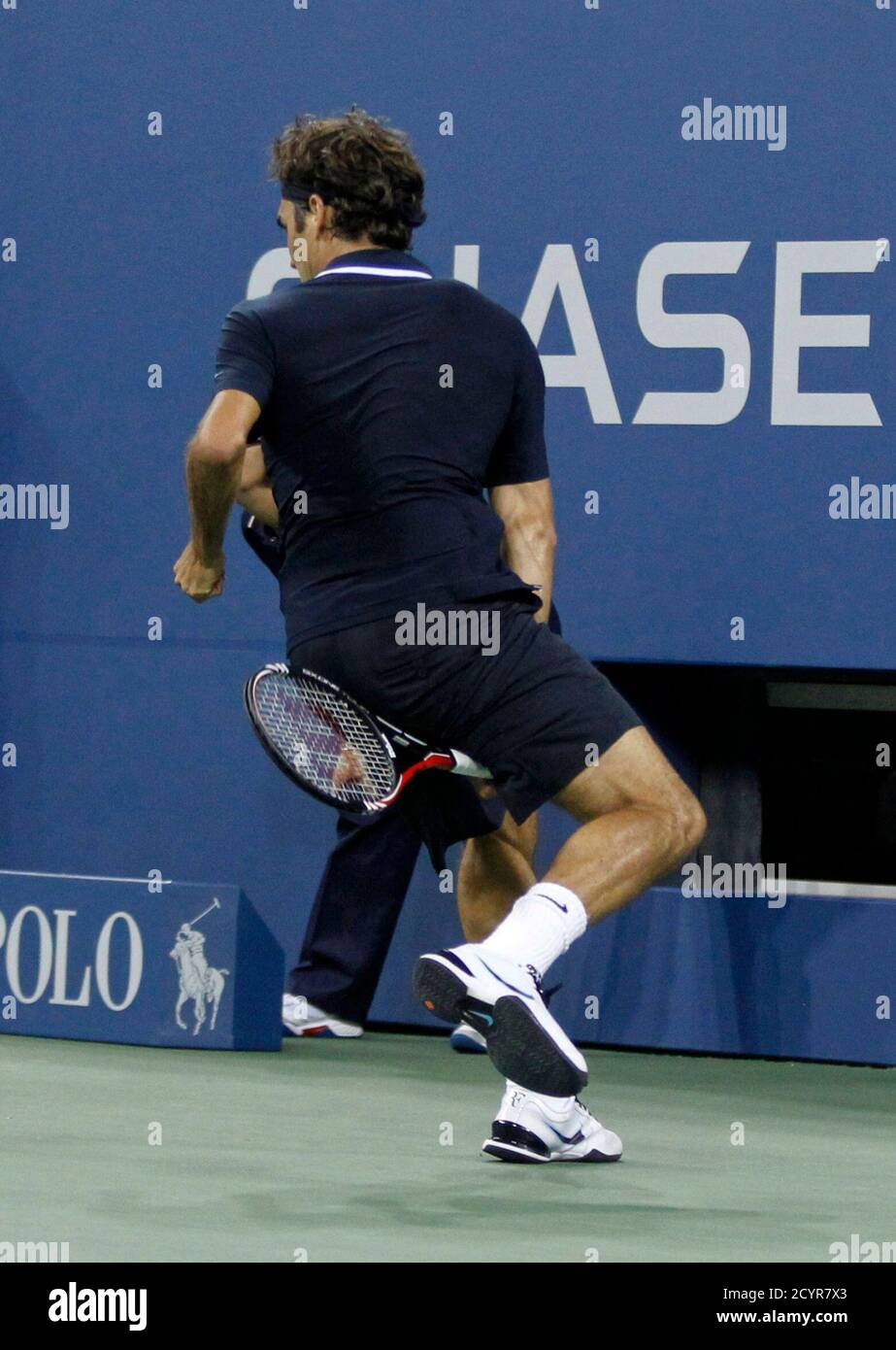 Roger Federer of Switzerland returns a winning shot between his legs while  playing Brian Dabul of Argentina during their opening night match at the  U.S. Open tennis tournament in New York, August