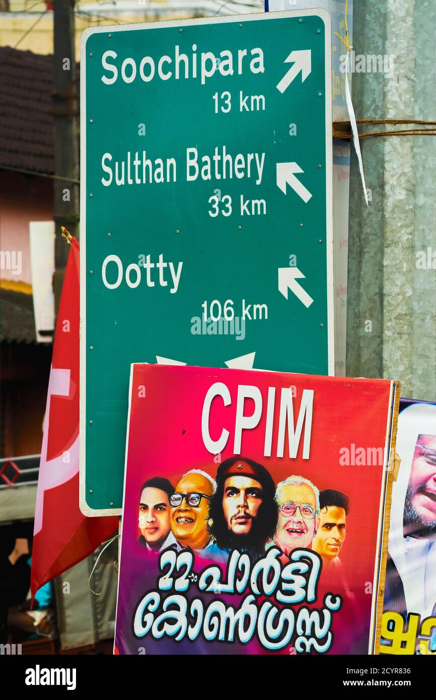 Communist Party poster of Che Guevara & Indian leaders, with road sign post in the northern Wayanad region; near Soochipara, Wayanad, Kerala, India Stock Photo