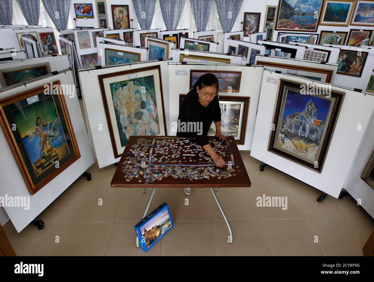 Filipino businesswoman Gina Lacuna pieces together a thousand-piece jigsaw  puzzle of La Seine, Paris, inside her museum in Tagaytay city, south of  Manila July 24, 2012. Lacuna collects and pieces together jigsaw