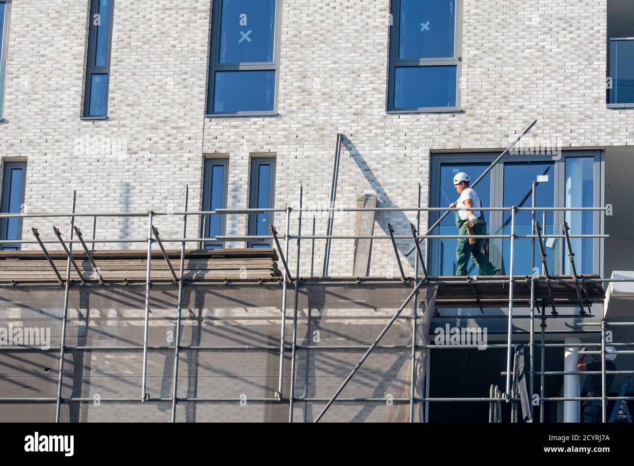 Building / dismantling scaffolding by construction worker for a new construction project Stock Photo