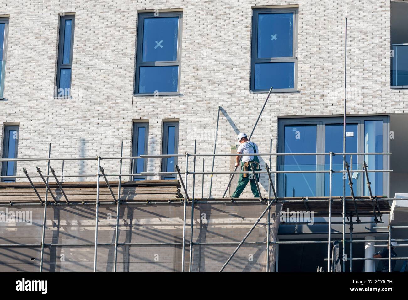 Building / dismantling scaffolding by construction worker for a new construction project Stock Photo