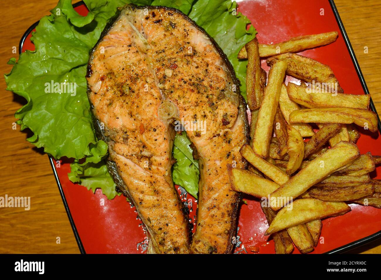 Grilled Steelhead trout with fries . Red dinner plate Stock Photo Alamy