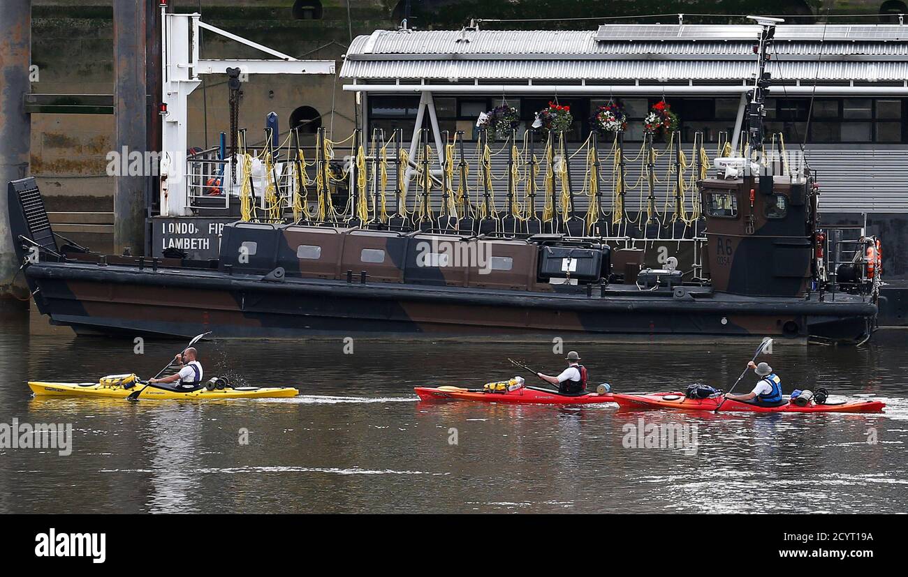 People paddle kayaks past a Landing Craft Unit from the Marine's 539 Assault Squadron which is moored on the Thames in central London July 19, 2012. REUTERS/Suzanne Plunkett (BRITAIN - Tags: SPORT OLYMPICS SOCIETY MILITARY) Stock Photo