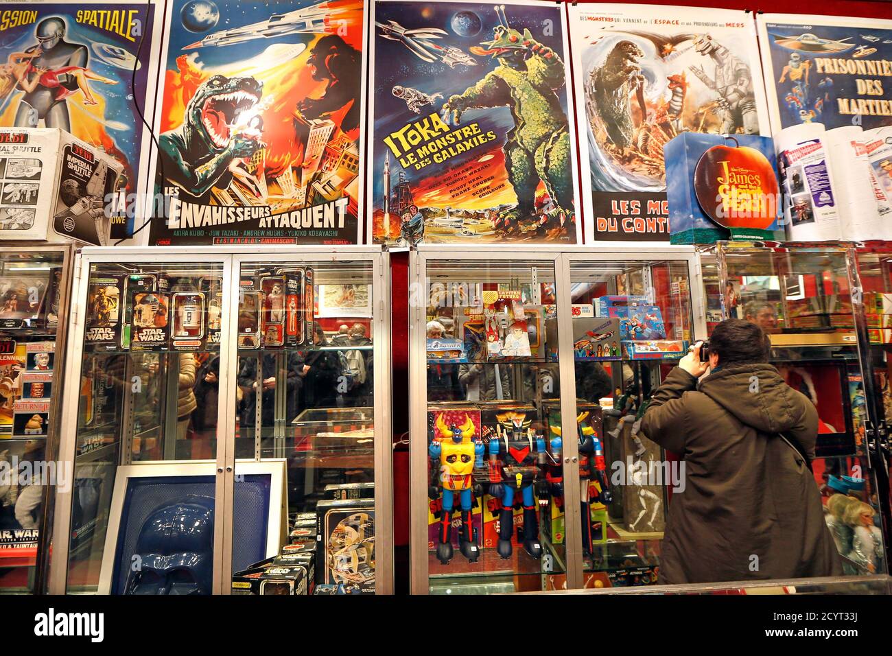 A man photographs a display case in a room with science fiction toys and  posters at the presentation of '1960-1980 Generation Jouets' before an  exceptional auction sale at Drouot auction house in