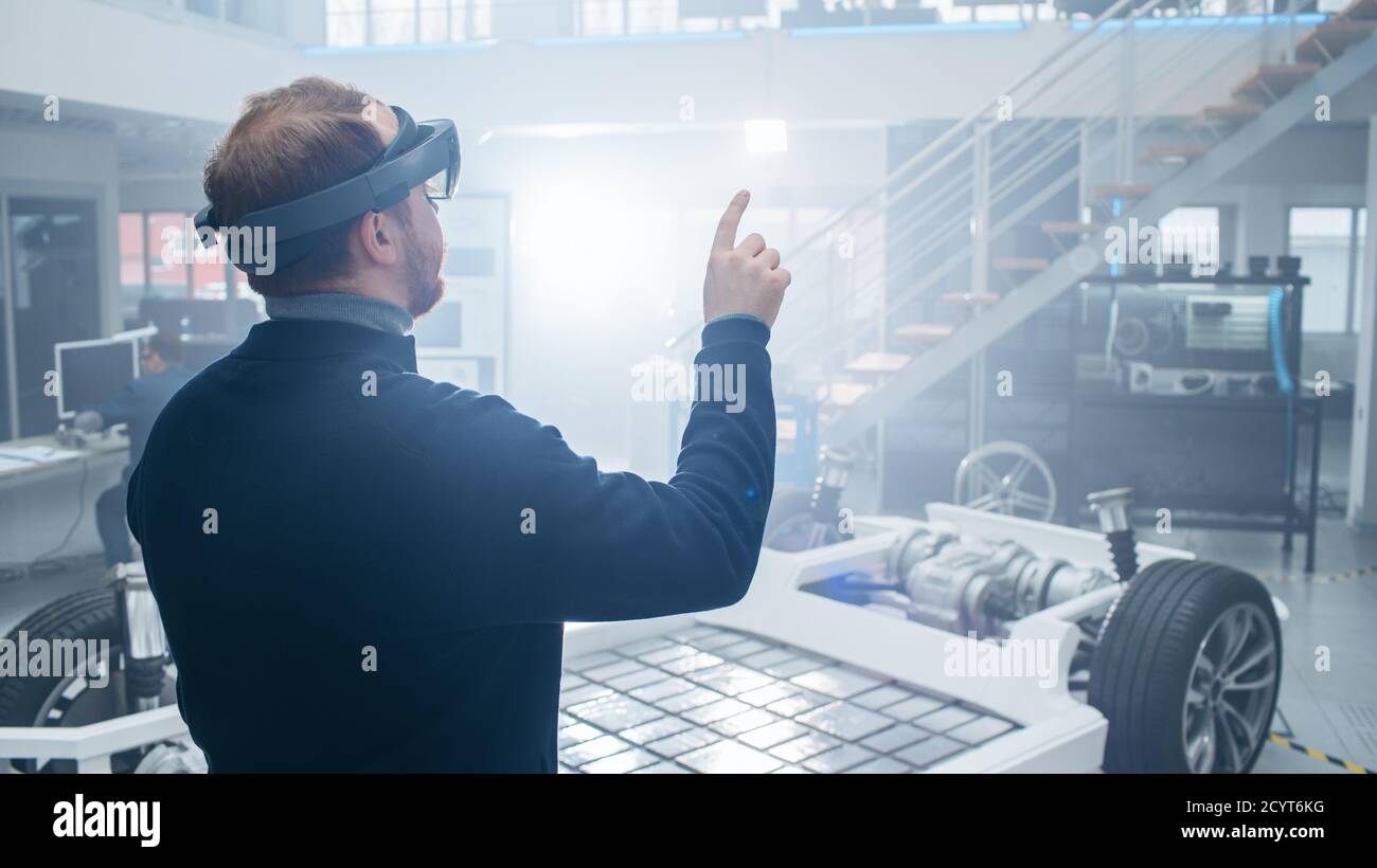 Automotive Engineer Using Augmented Reality Headset and Making Touching Gestures of a Virtual Buttons in the Air. In Innovation High Tech Laboratory Stock Photo