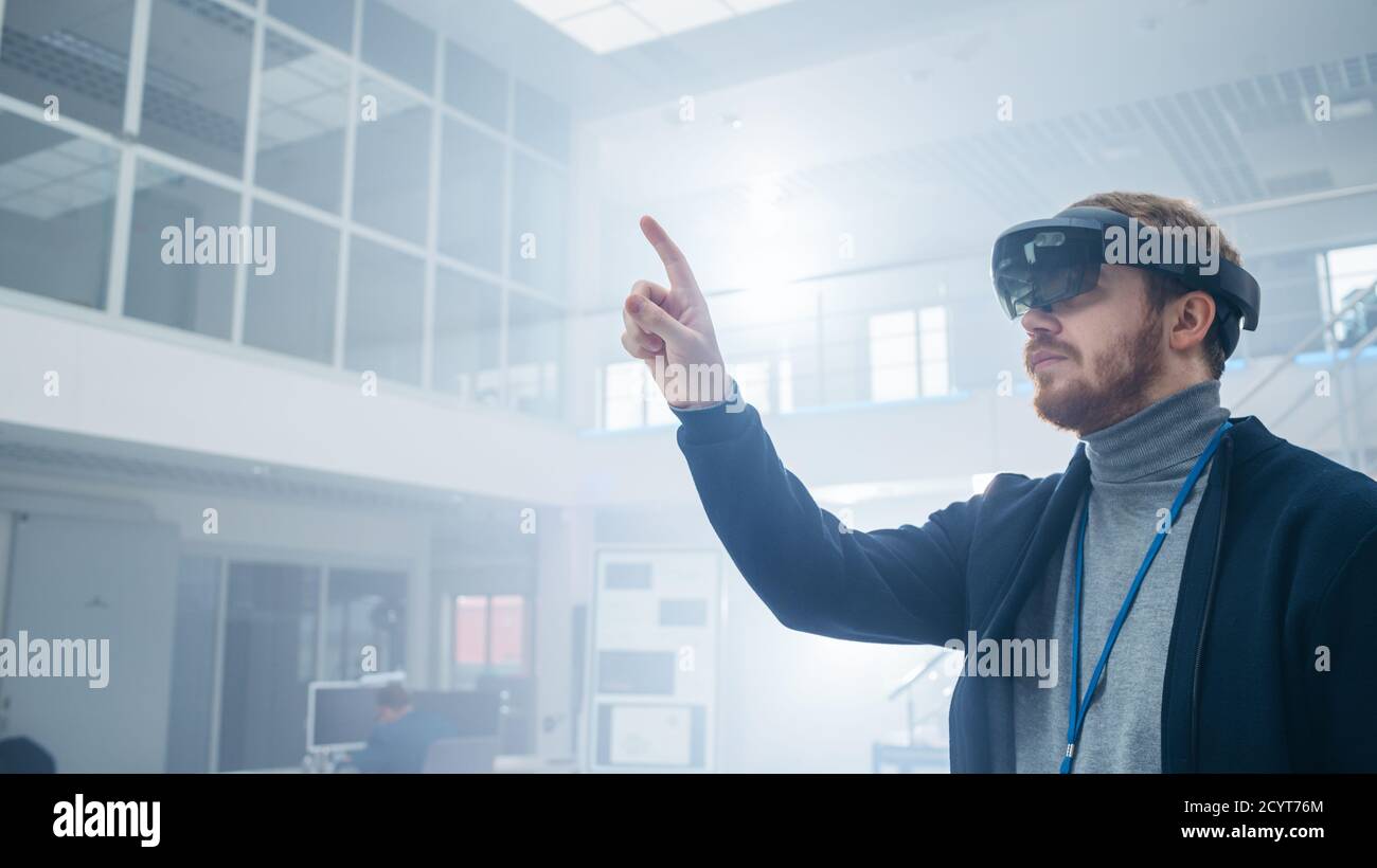 Automotive Engineer Using Augmented Reality Headset and Making Touching Gestures of Virtual Objects in the Air. In Innovation High Tech Laboratory Stock Photo