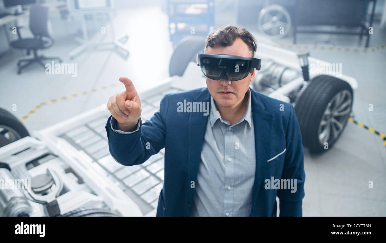 Automotive Engineer Using Augmented Reality Headset Making Touching Gestures. In Innovation Laboratory Facility Concept Vehicle Frame Includes Wheels Stock Photo