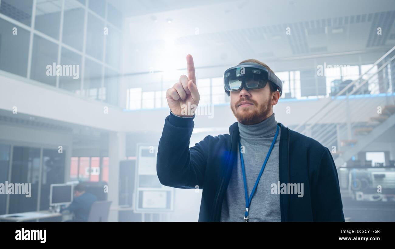 Automotive Engineer Using Augmented Reality Headset and Making Touching Gestures of Virtual Objects in the Air. In Innovation High Tech Laboratory Stock Photo