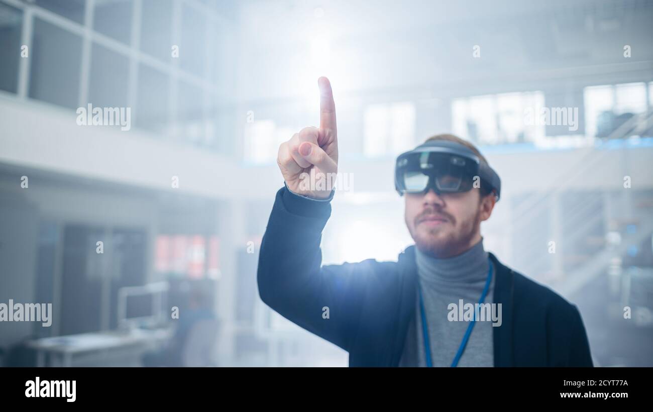 Automotive Engineer Using Augmented Reality Headset and Making Touching Gestures of Virtual Objects in the Air. In Innovation High Tech Laboratory Stock Photo