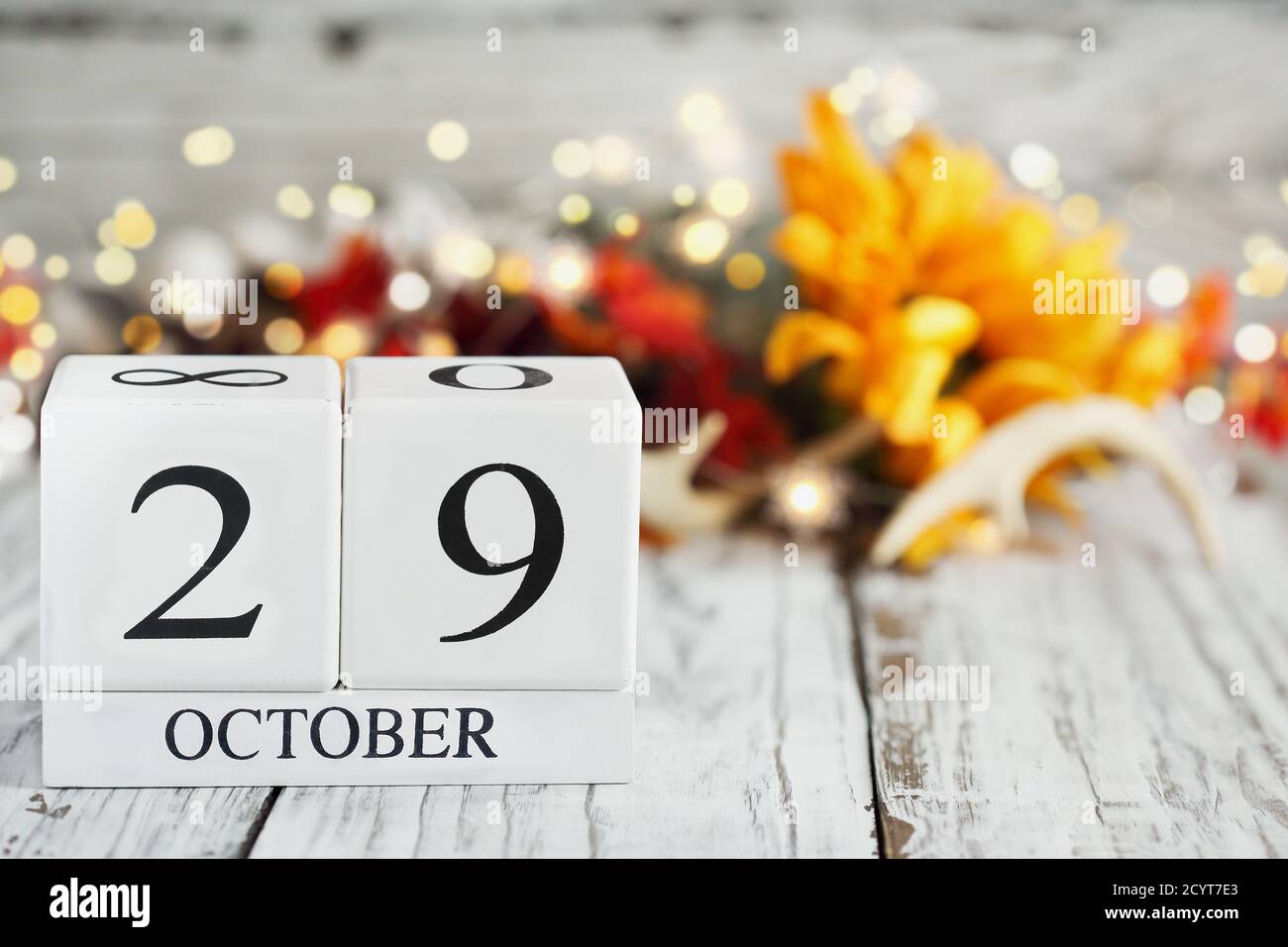 White wood calendar blocks with the date October 29th and autumn decorations over a wooden table. Selective focus with blurred background. Stock Photo