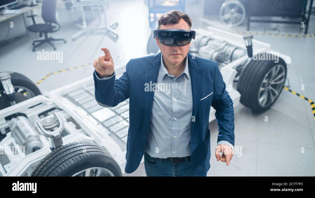 Automotive Engineer Using Augmented Reality Headset Making Touching Gestures. In Innovation Laboratory Facility Concept Vehicle Frame Includes Wheels Stock Photo