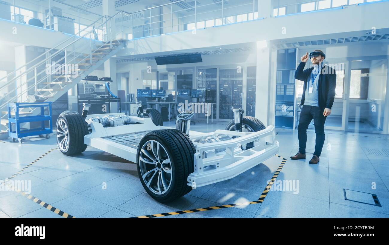 Automotive Engineer Working on Electric Car Chassis Platform, Using Augmented Reality Headset. In Innovation Laboratory Facility Concept Vehicle Frame Stock Photo