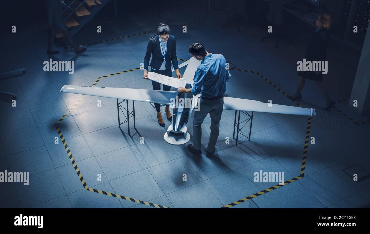 Team of Industrial Aerospace Engineers Work On Unmanned Aerial Vehicle Concept. Designers Work on Pilotless Drone. Industrial Facility with Aircraft Stock Photo