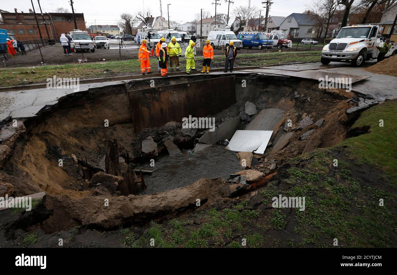 Workers look into a sinkhole caused by a broken water main in Chicago, Illinois, April 18, 2013.  Heavy rains and flooding brought havoc to the Chicago area on Thursday, shutting major expressways, delaying commuter trains for hours, cancelling flights, flooding basements and closing dozens of suburban schools. On the city's South Side, a sinkhole opened up on a residential street, swallowing three cars, according to Officer Mike Sullivan of the Chicago Police Department. One person was hospitalized with non-life-threatening injuries. REUTERS/Jim Young   (UNITED STATES - Tags: ENVIRONMENT TPX  Stock Photo