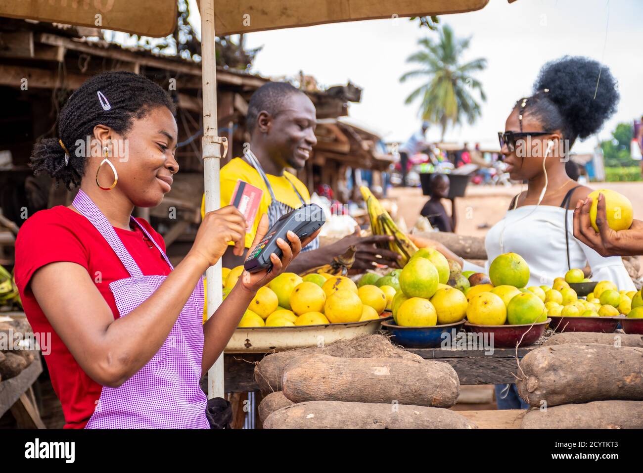 people in a local african market, trader swiping a credit card on a pos