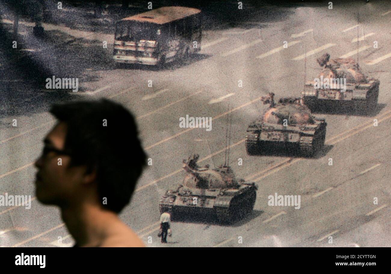 A man walks past a banner, printed with a photo of a man standing in front of tanks during the 1989 military crackdown on pro-democracy protesters around Beijing's Tiananmen Square, at Hong Kong's Victoria Park June 4, 2009. Tens of thousands of people are expected to attend a candlelight vigil later in the evening to commemorate those who died in the crackdown. REUTERS/Tyrone Siu (CHINA ANNIVERSARY CONFLICT POLITICS) Stock Photo