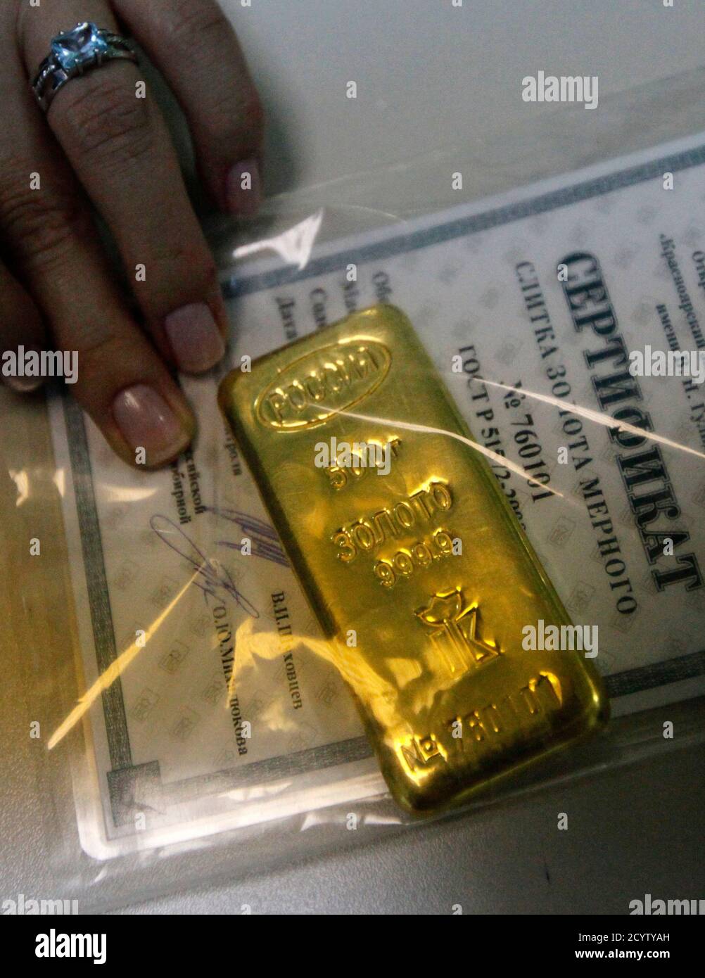 A bank employee holds a 500 gram high purity 999.9 hallmark gold ingot  before selling it to a client at a Sberbank office in Russia's Siberian  city of Krasnoyarsk August 12, 2011.