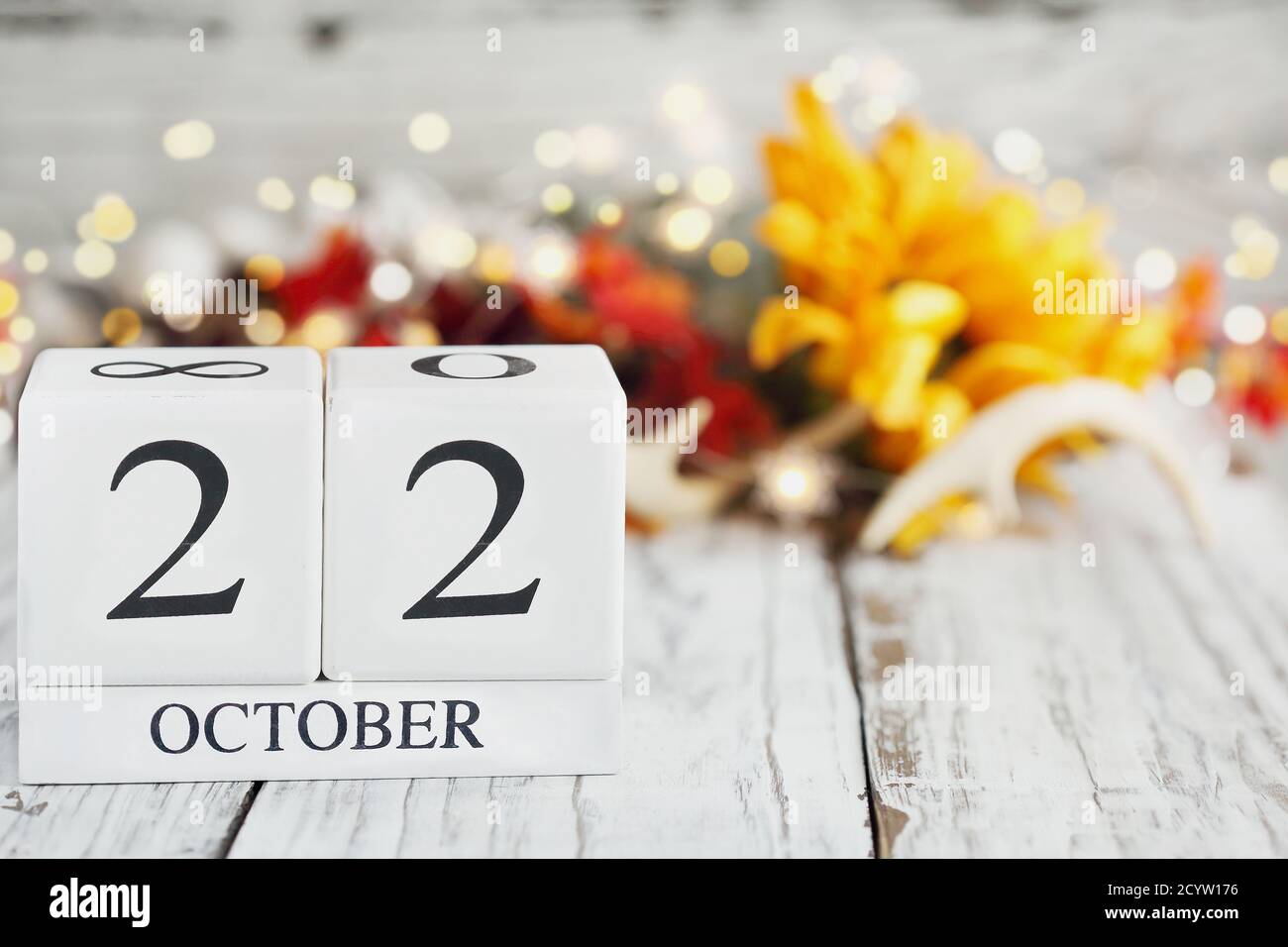 White wood calendar blocks with the date October 22nd and autumn decorations over a wooden table. Selective focus with blurred background. Stock Photo