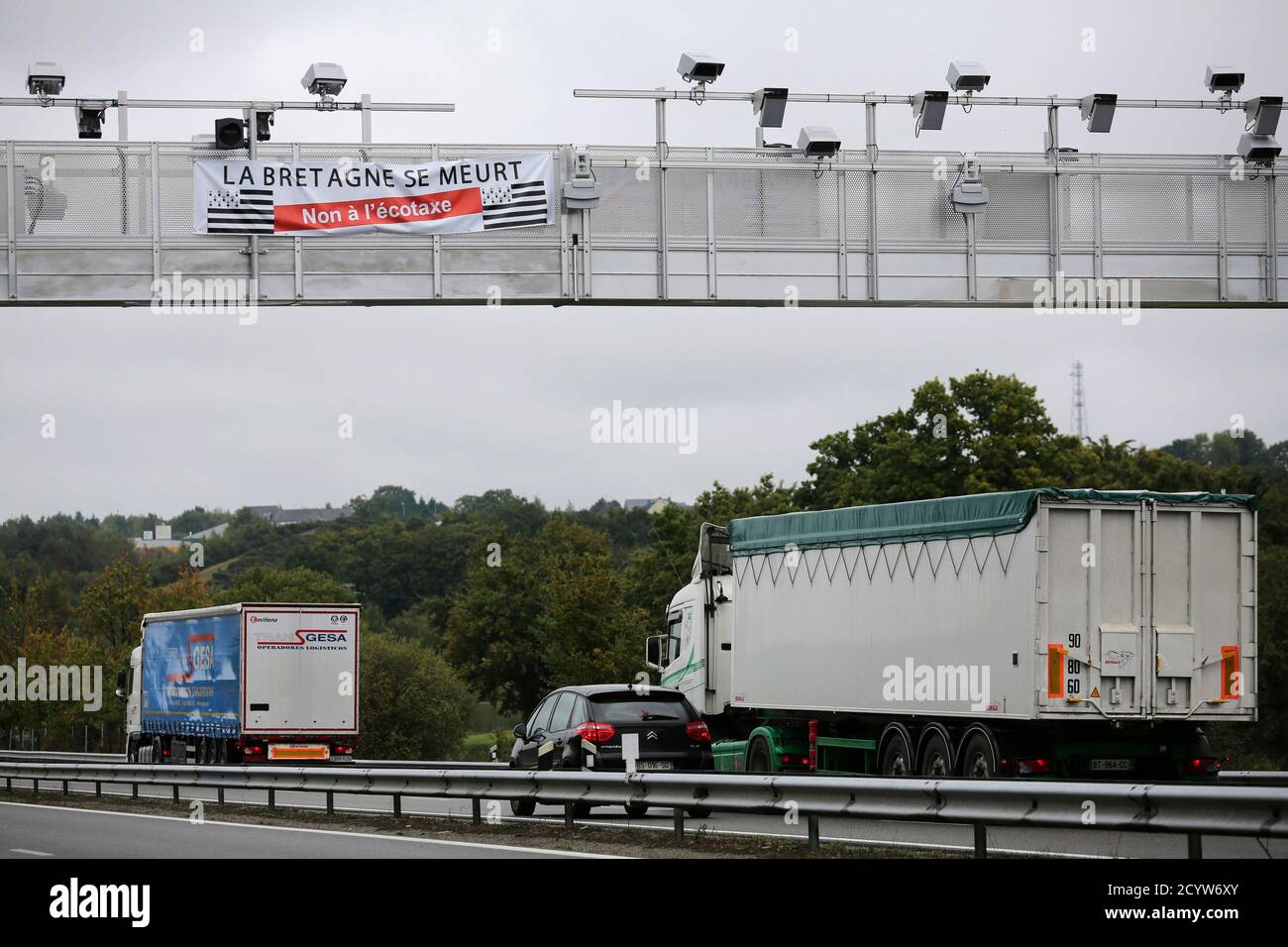Cars and truck passes under an ecotax control portal in Bain-de-Bretagne, western France, October 15, 2013. French farmers protest the future tax on truck transport of their produce. The banner reads 'Brittany is dying, No ecotaxe'.  Picture taken October 15, 2013    REUTERS/Stephane Mahe (FRANCE - Tags: BUSINESS POLITICS TRANSPORT AGRICULTURE) Stock Photo