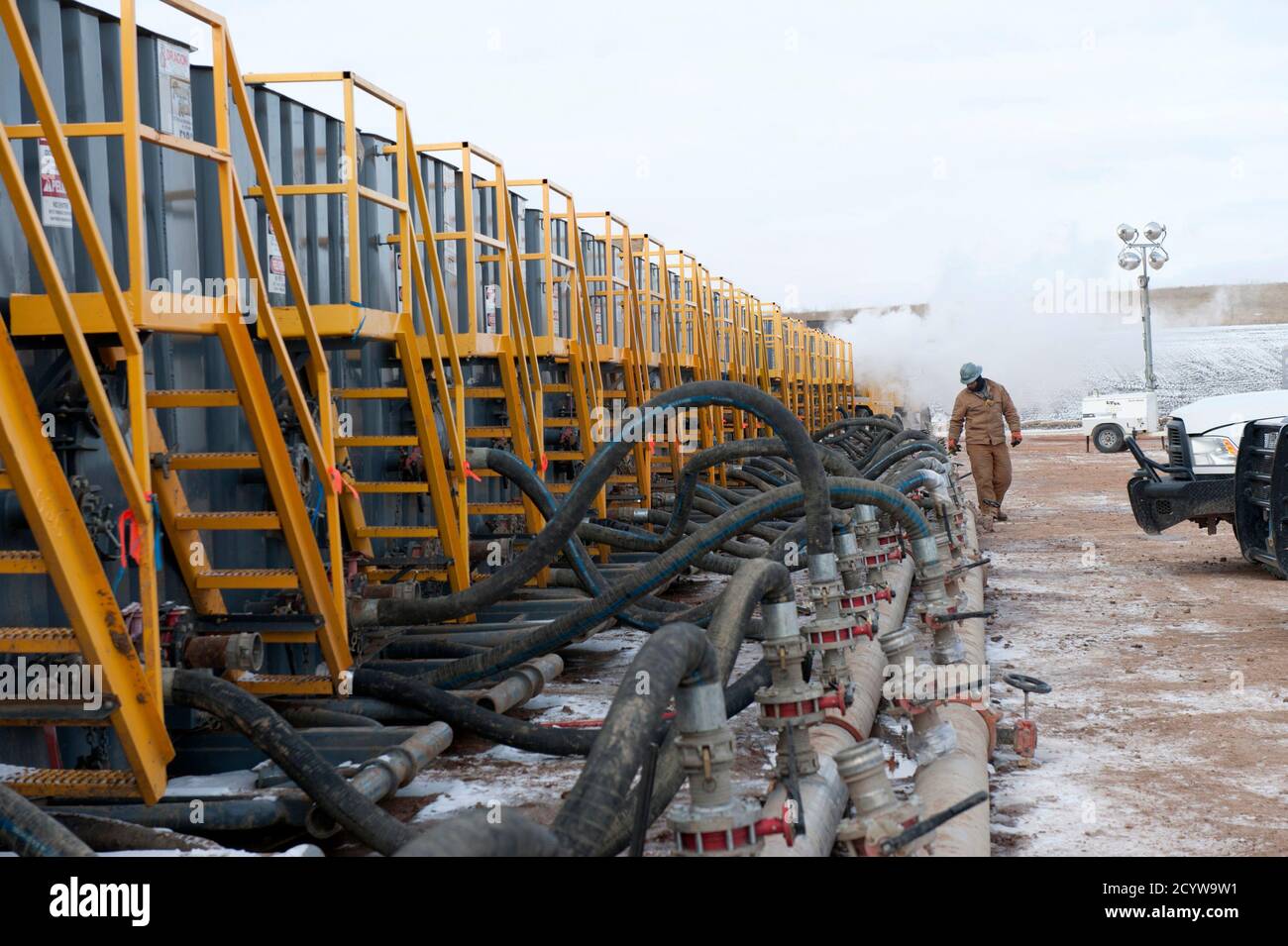 A worker monitors water tanks at a Hess fracking site near Williston, North Dakota November 12, 2014.  Falling oil prices have yet to spoil North Dakota's party, with billions of investment dollars still flowing for new wells and pipelines, apartments and shopping centers, a tacit bet the third energy boom in the state's history is just getting started.   REUTERS/Andrew Cullen (UNITED STATES  - Tags: BUSINESS COMMODITIES ENERGY) Stock Photo