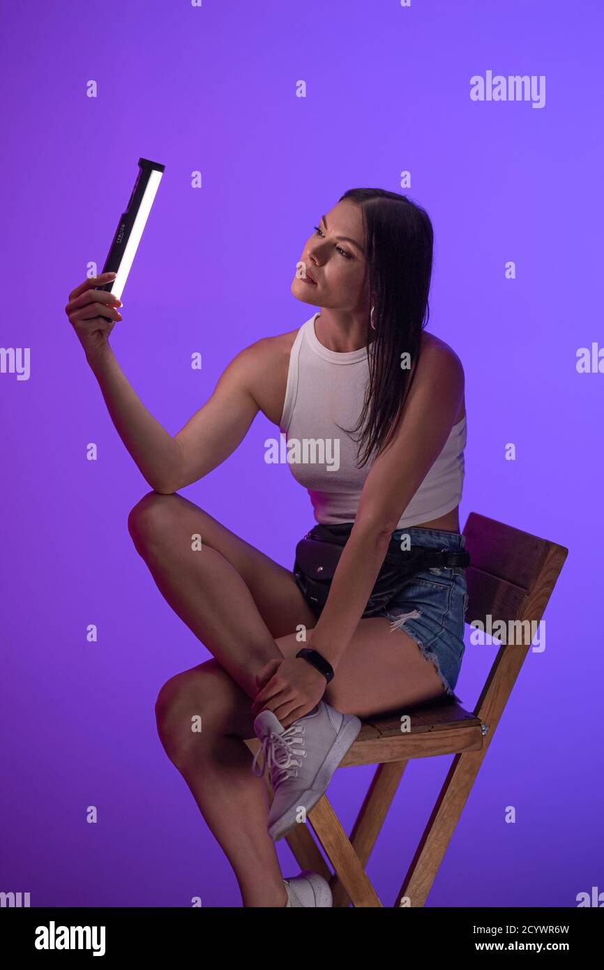 Young woman sits on chair holding lamp. Presentation of Nanlite Studio LED Lighting. Backstage of presentation. June 2020, Kyiv Ukraine. High quality Stock Photo