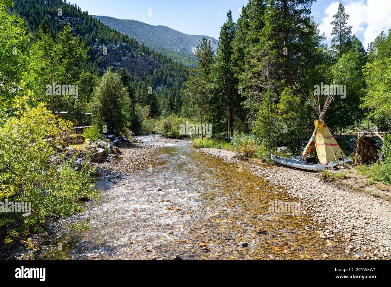 A small teepee and empty canoe sit by a small Colorado creek i Stock Photo
