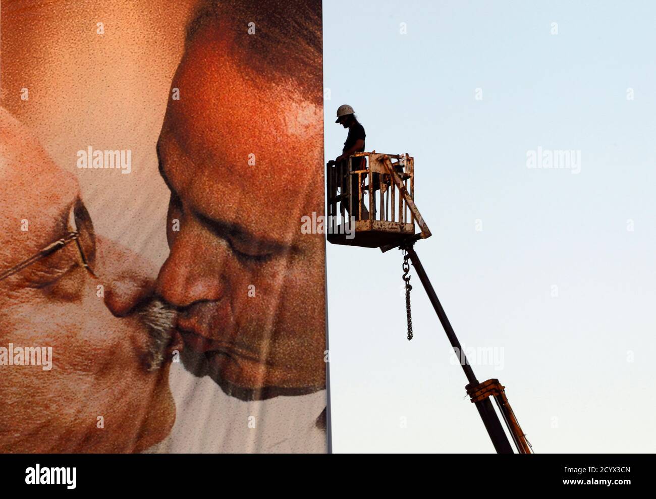A worker installs a Benetton billboard advertisement showing a composite  image of Israeli Prime Minister Benjamin Netanyahu (R) kissing Palestinian  President Mahmoud Abbas in Tel Aviv November 28, 2011. The image, part