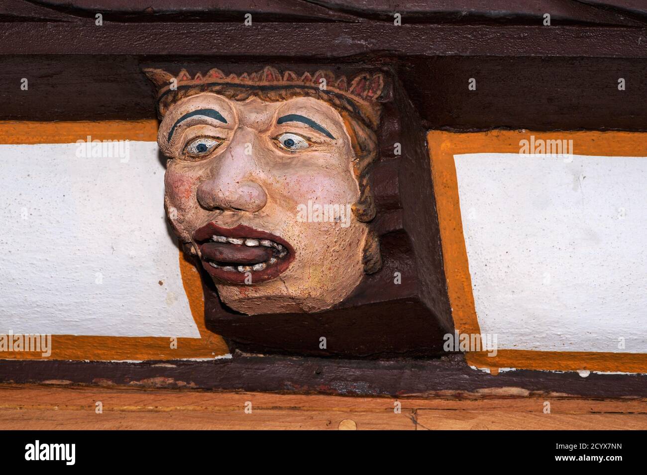 Gluttony, one of Christianity’s Seven Deadly Sins, represented in the sculpted end of a wooden ceiling beam protruding from the timber-framed Haus der Sieben Laster (House of the Seven Vices) at Brückengasse 9 in Limburg an der Lahn, Hesse, Germany.  The ancient house, rebuilt in 1567, served as a family home, a provisions shop, an ironmongery and a shoe shop before being renovated in the modern era and opened to the public as a museum. Stock Photo