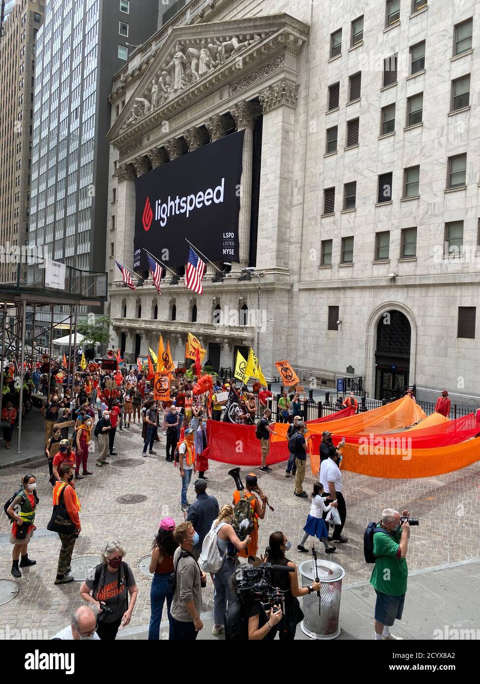 Colored fabrics representing the terrible fires in the west and the Amazon in Brazil lead a march past the New York Stock Exchange telling big corporations that we must fight to preserve the earth our home now before it is too late. Stock Photo