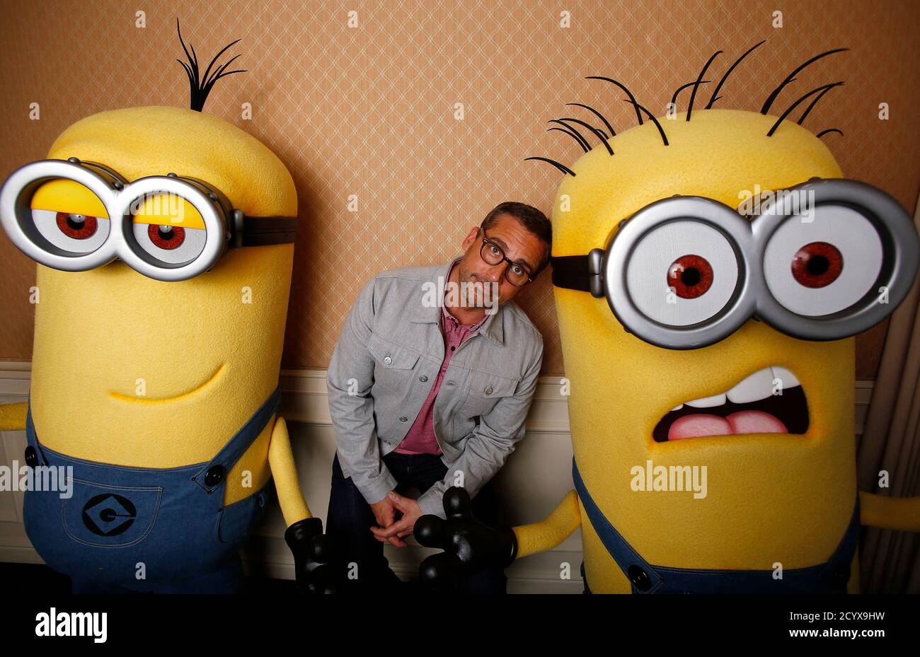 Actor Steve Carell poses with two life-size minion characters while  promoting his upcoming movie 