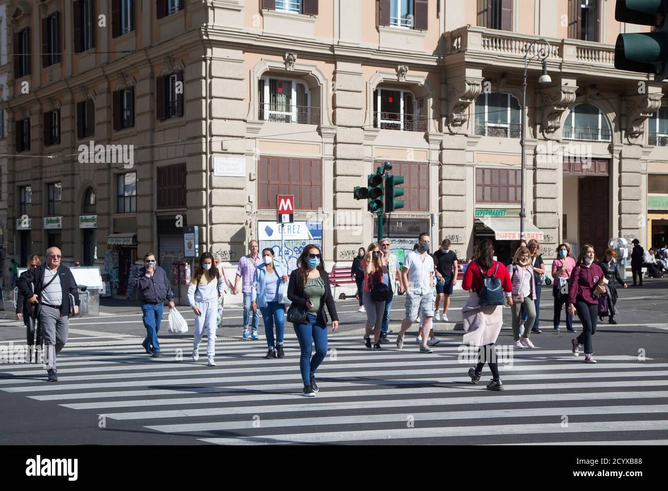 ROME, ITALY - OCTOBER 01 2020: Commuters, wearing protective face masks, cross a road in Rome, Italy. Stock Photo