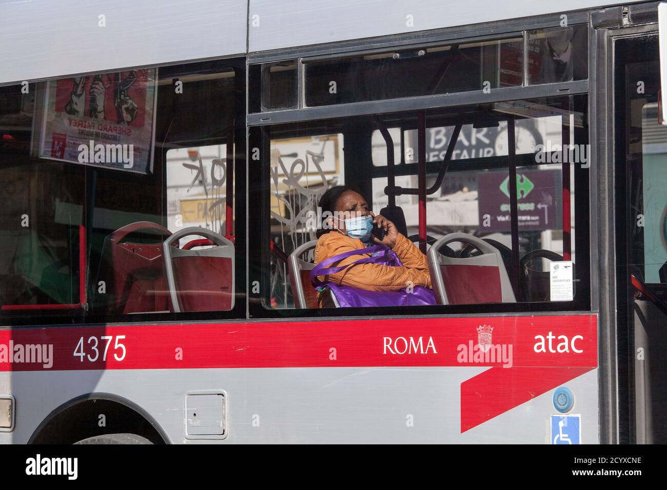 ROME, ITALY - OCTOBER 01 2020: A passenger, wearing a protective face mask, sits inside a bus in Rome, Italy Stock Photo