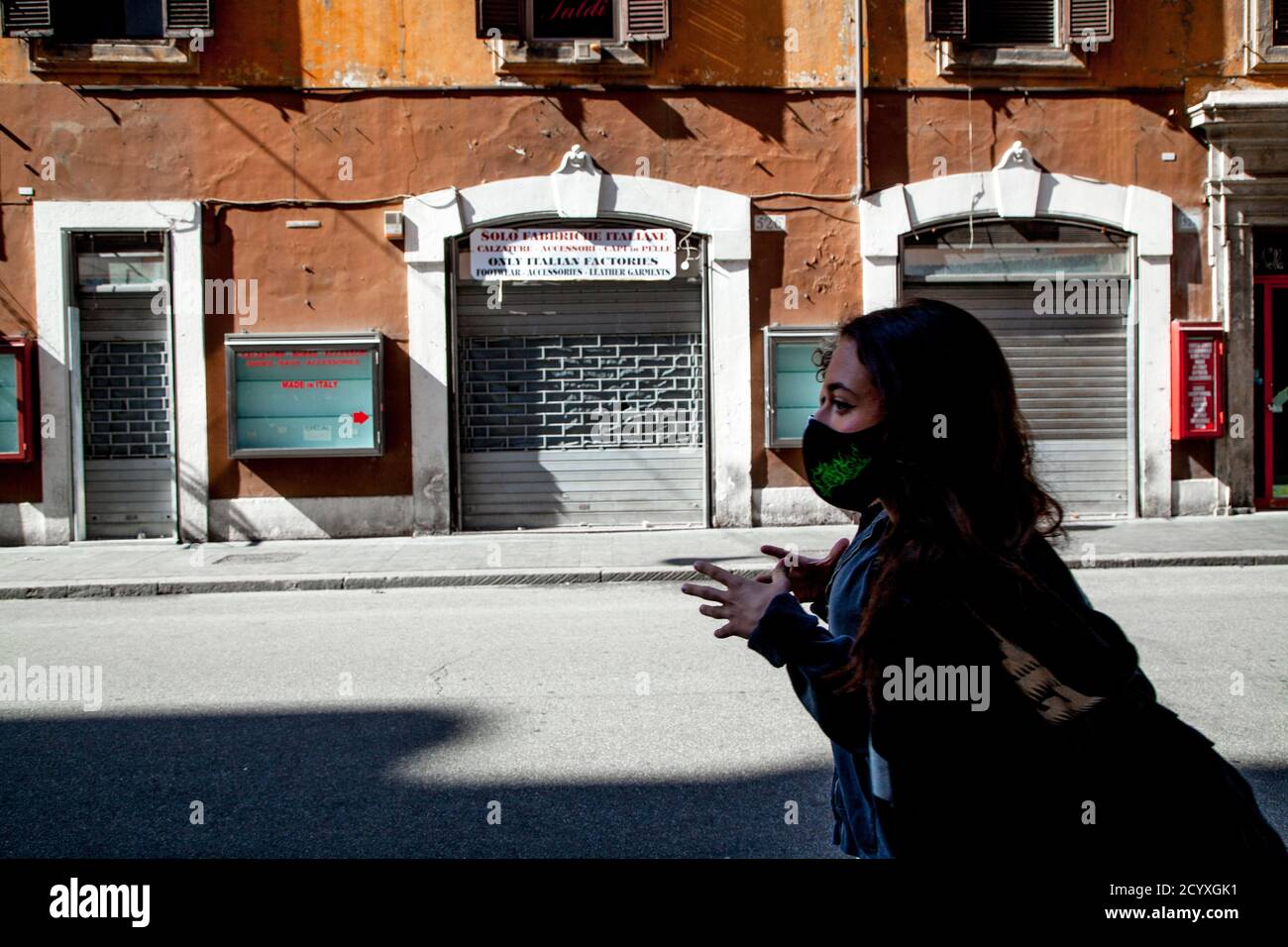 ROME, ITALY - OCTOBER 01 2020: A pedestrian, wearing a protective face mask, carries a shopping bag in Romes Via del Corso, Italy. Stock Photo