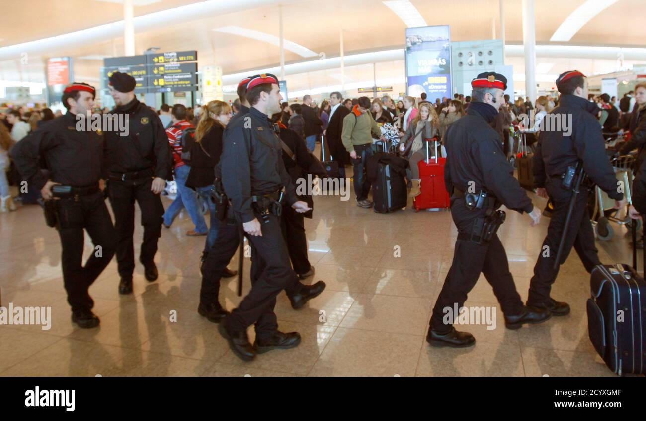 Catalunya Autonomous Police, known locally as Mossos D'esquadra, patrol past stranded passengers in Barcelona's El Prat T1 airport after flights were cancelled due to a massive walkout of air traffic controllers December 4, 2010. Spanish airspace reopened on Saturday after a wildcat strike by air traffic controllers paralysed airports for a second day and the government declared its first state of emergency in the post-Franco era.     REUTERS/Gustau Nacarino (SPAIN - Tags: CIVIL UNREST EMPLOYMENT BUSINESS TRANSPORT POLITICS) Stock Photo