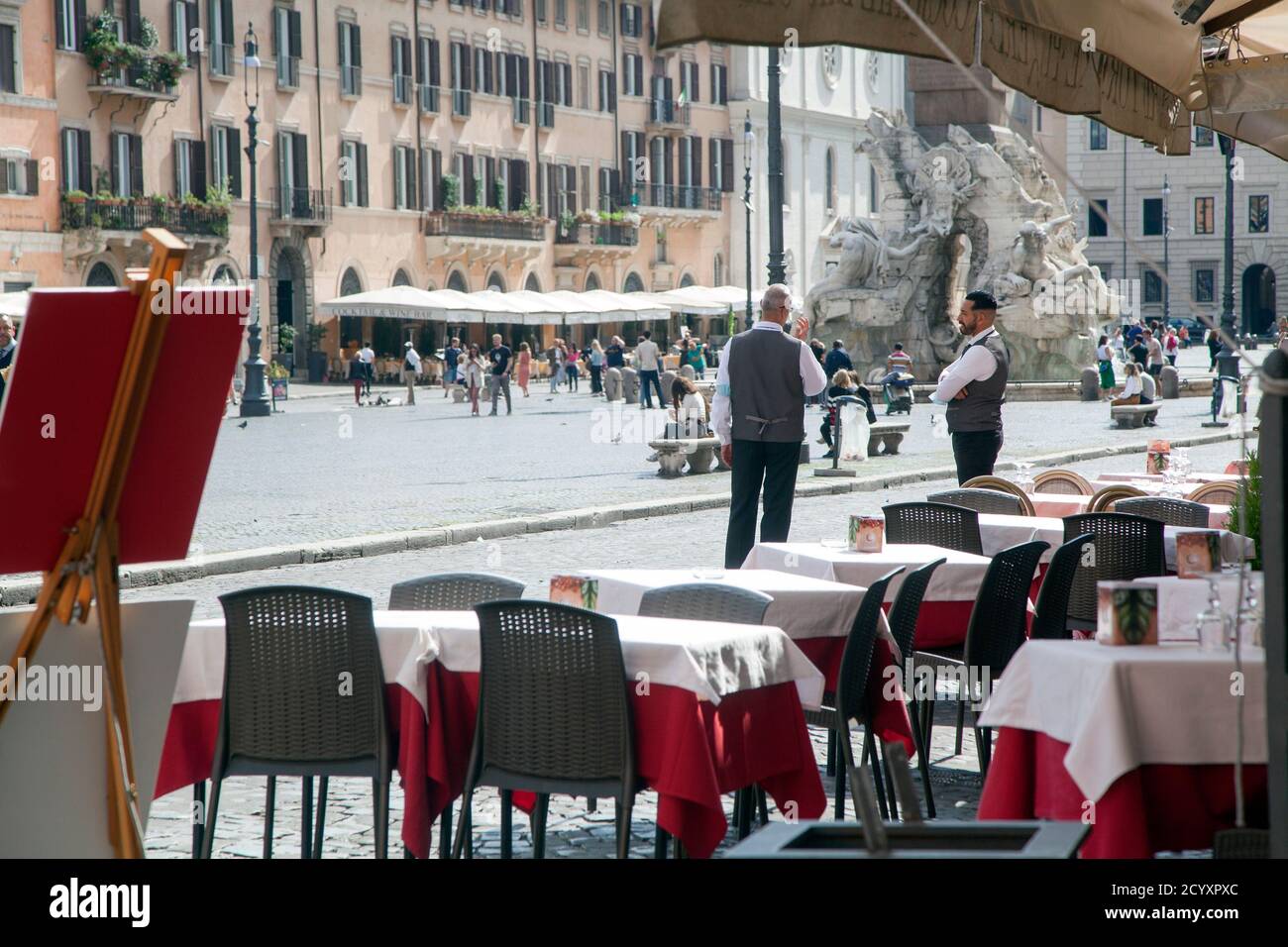 ROME, ITALY - OCTOBER 01 2020: Waiters wait for customers outside a restaurant in Navonas square in Rome. Italy's economy is forecast to shrink 9% this year. Stock Photo