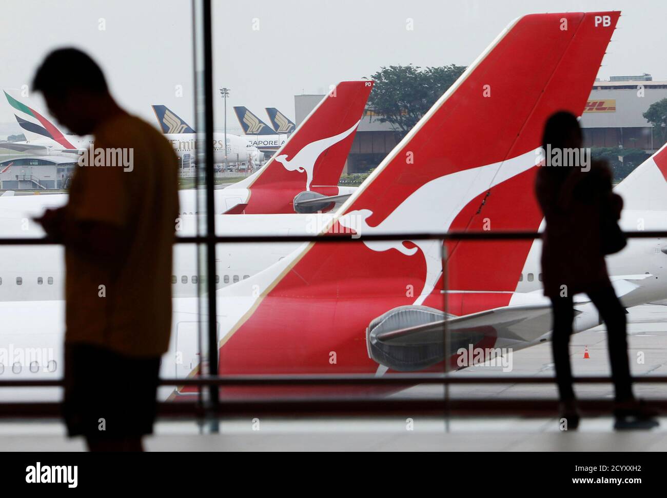 A woman looks at Qantas planes sitting on the tarmac at a viewing gallery at Singapore's Changi Airport August 20, 2013. Singapore's ambitious project to double its air passenger handling capacity by the mid-2020s is set to extend its lead over neighbours like Kuala Lumpur, Bangkok and Jakarta, whose airports are struggling with congestion and construction delays. Changi, Southeast Asia's biggest and most popular international airport, is keen to seize a greater share of a boom in regional traffic, mindful of competitors' plans to grow into international hubs. Picture taken August 20, 2013. To Stock Photo