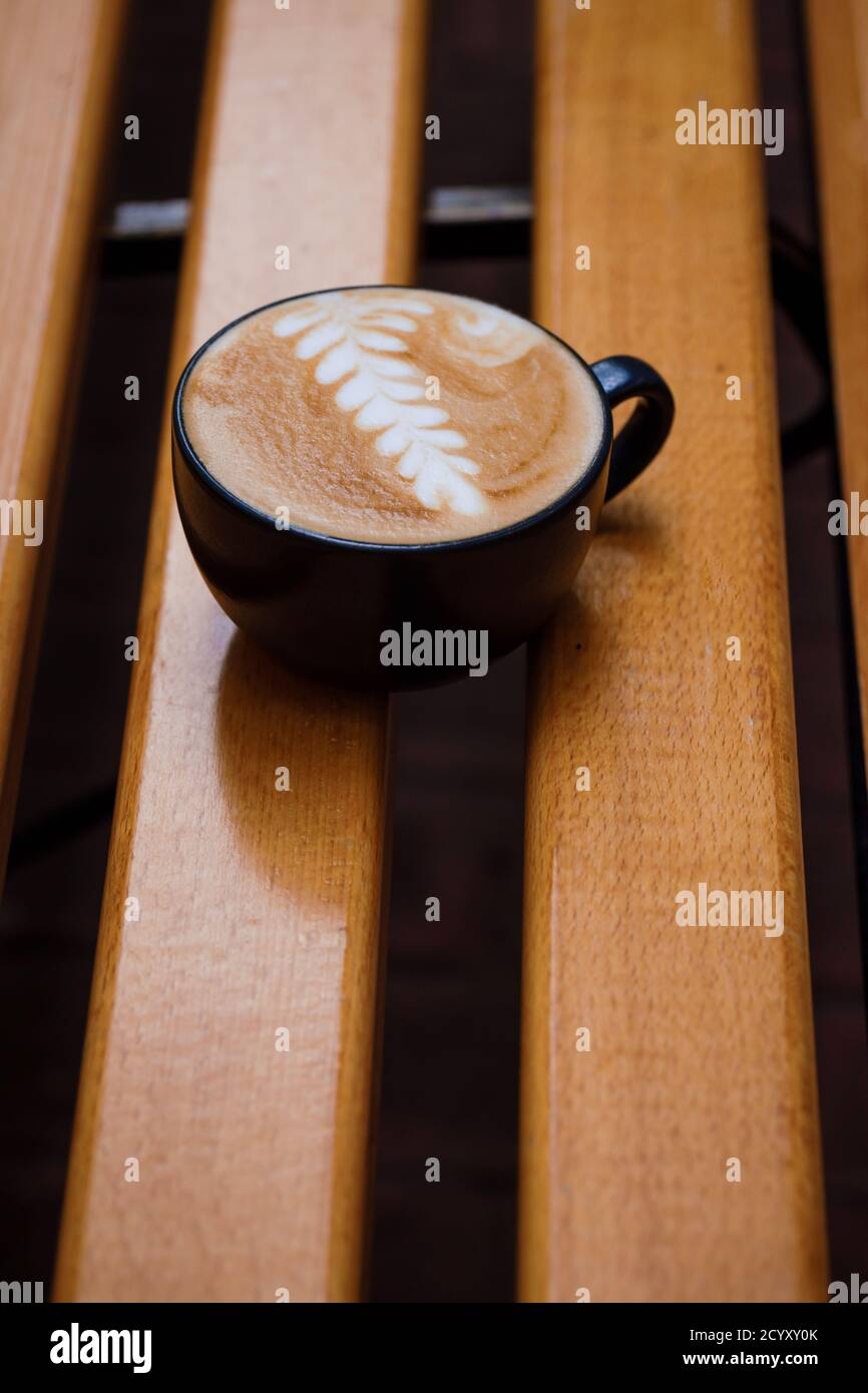 Cup of cappuccino with a pattern on a wooden bench. Stock Photo