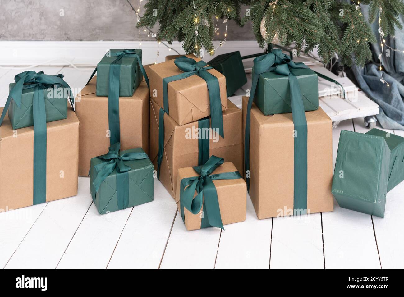 New Year's gifts lie on the floor under the Christmas tree. They are packed in green paper and wrapped in green ribbon. High quality photo Stock Photo