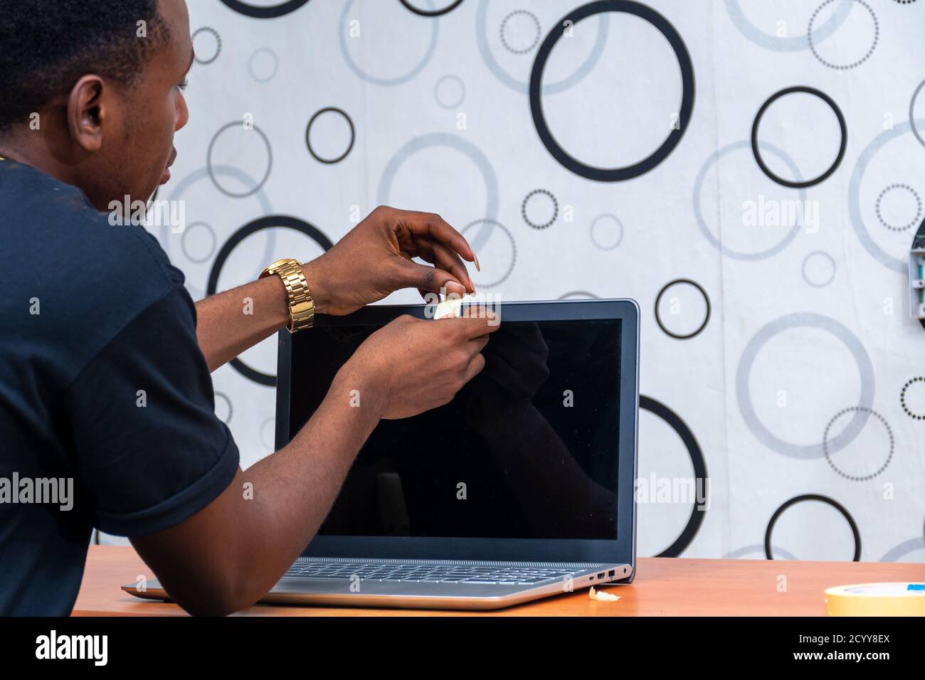 black man putting a piece of tape over his laptop computer webcam Stock ...