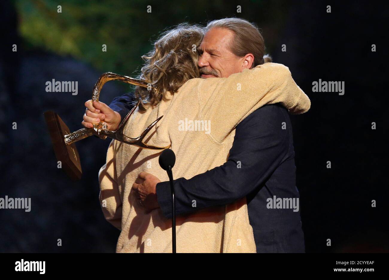 Actor Jeff Bridges R Embraces Actor Jake Gyllenhaal Dressed Like The Character Of The Dude From