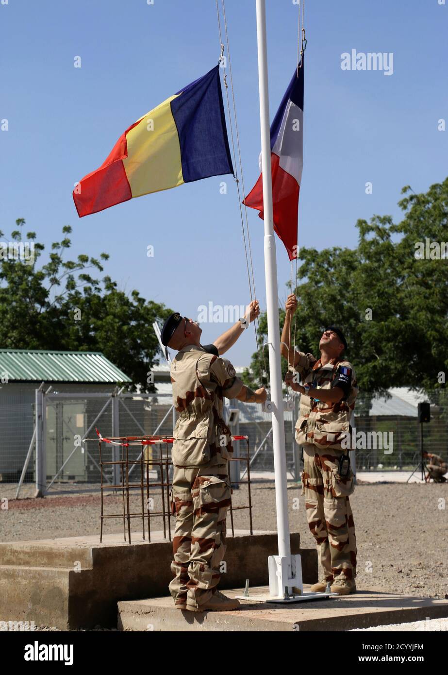 French soldiers raise the French and Chadian flags at their military base in Chadian capital N?Djamena, October 26, 2014. Chad's army is considered one of Africa's most battle-ready and played a frontline role alongside the French in an operation in 2013 against Islamic fighters in Mali's desert north. In recent months, Chad has changed its attitude to Boko Haram. Chadian forces are stepping up surveillance and have made several arrests, residents and security sources say. It has also pledged 700 troops for a cross-border force in the Lake Chad region to counter the group, due to start operati Stock Photo