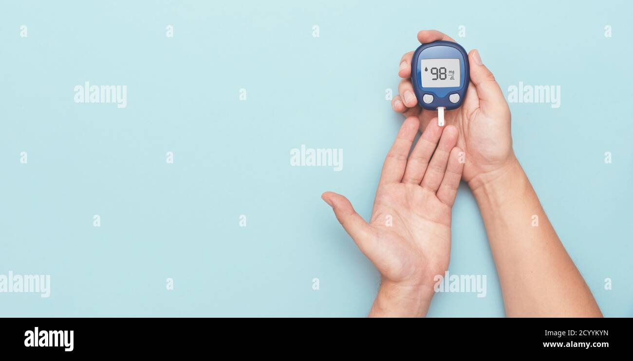 Man Using Glucometer Man using glucometer, checking blood sugar level. Wide image with copy ...
