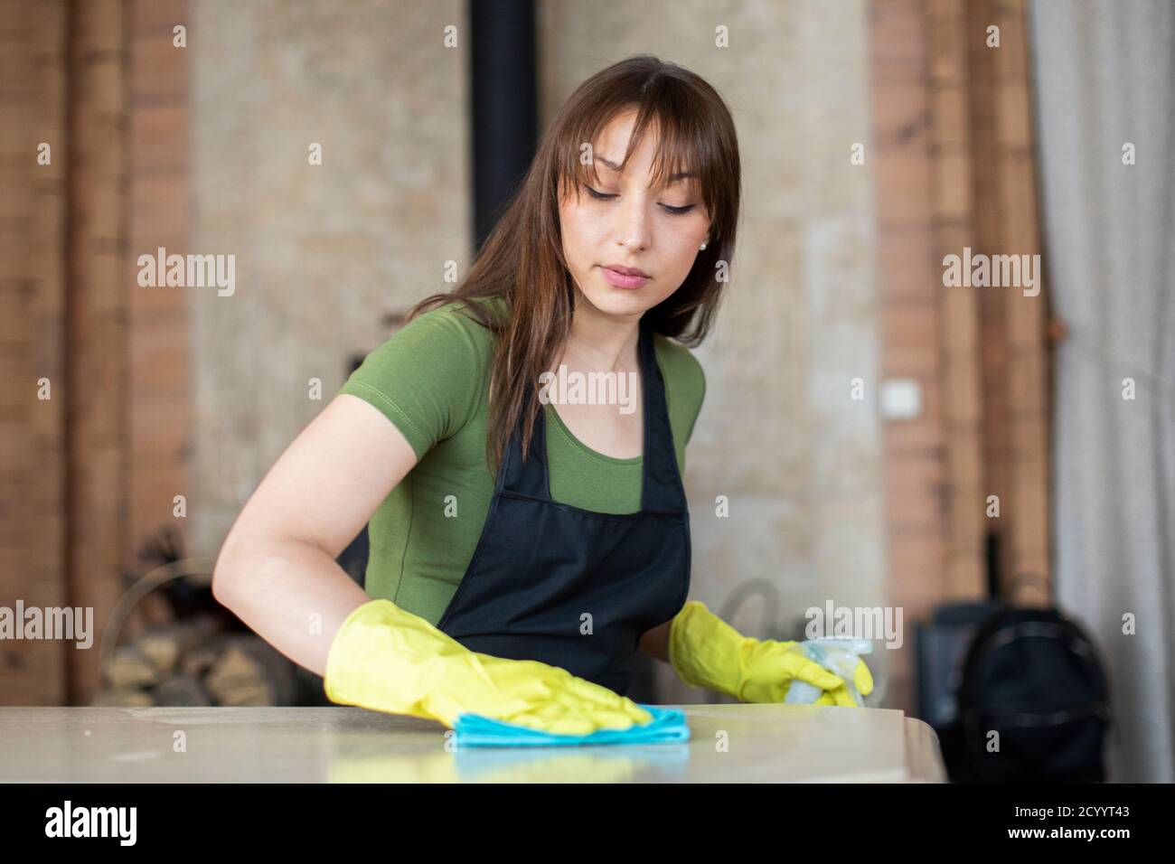 Beautiful woman in black apron cleaning house, rubs dust using ...