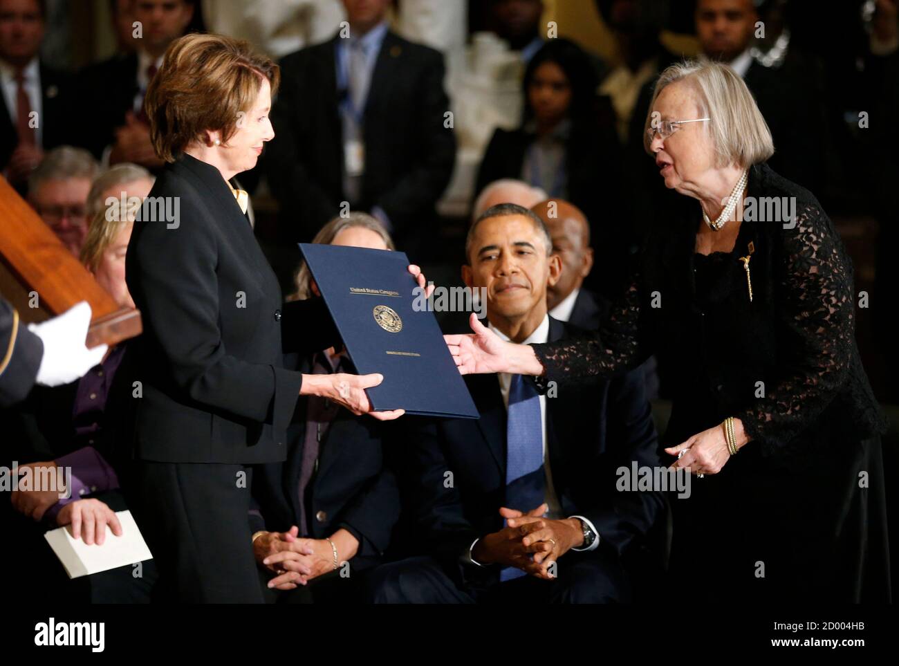 U.S. President Barack Obama (C) watches as former Speaker of the House  Nancy Pelosi (L) hands Heather Foley a resolution during a memorial service  for her husband, former Speaker Tom Foley, in